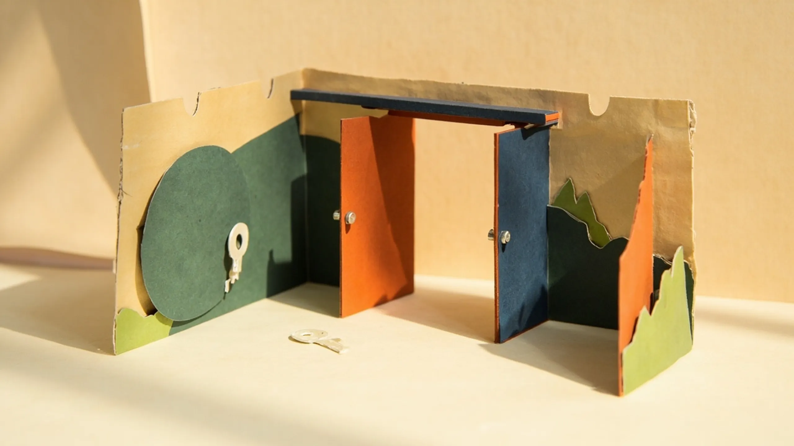 Paper-cutout illustration of a fortified checkpoint gate with two colored doors and a large shield leaning against it
